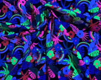 May include: Blacklight fabric with a tropical print featuring toucans, palm trees, rainbows, and flowers in bright neon colors on a black background.  The fabric is folded in the center.