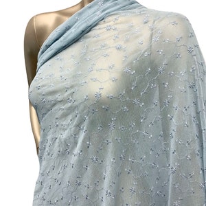 May include: Light blue sheer fabric with a delicate floral embroidery pattern. The fabric is soft and lightweight, making it ideal for a variety of sewing projects.