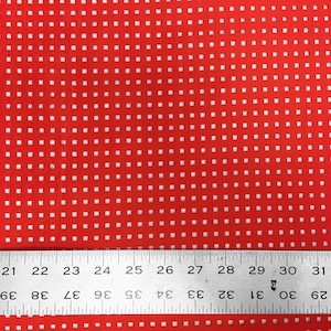 May include: Red fabric with a white grid pattern. A ruler is placed at the bottom of the image with the numbers 21 to 31 visible.