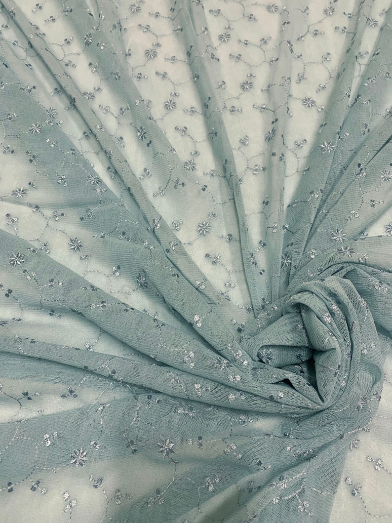 May include: A light blue sheer fabric with a delicate floral pattern embroidered in silver thread. The fabric is draped and gathered, showcasing its texture and drape.