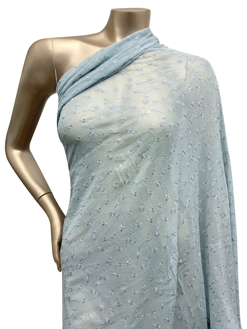May include: Light blue sheer fabric with a delicate white floral embroidery pattern.