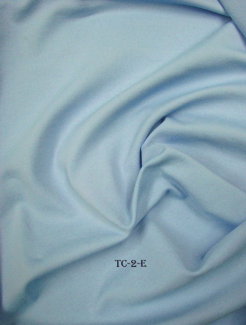 Puede incluir: Un primer plano de una tela azul claro con una textura suave. La tela est&aacute; doblada y drapeada, mostrando su naturaleza suave y fluida. El texto "TC-2-E" est&aacute; impreso en negro sobre la tela.