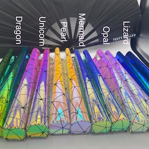 Puede incluir: Primer plano de ocho rollos de vinilo hologr&aacute;fico iridiscente con un patr&oacute;n de telara&ntilde;a negra. Los rollos est&aacute;n etiquetados como "Dragon", "Unicornio", "Perla", "Sirena", "&Oacute;palo", "Lagarto", "Festy" y "Fills".