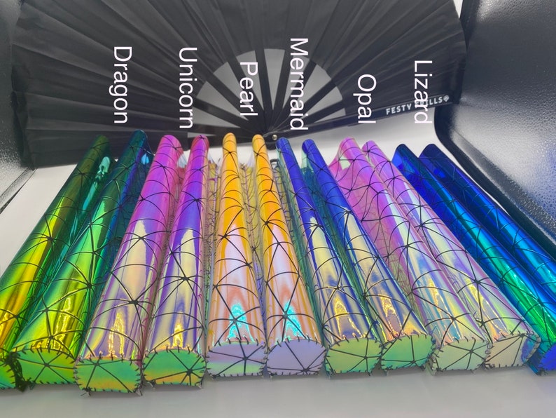Puede incluir: Primer plano de ocho rollos de vinilo hologr&aacute;fico iridiscente con un patr&oacute;n de telara&ntilde;a negra. Los rollos est&aacute;n etiquetados como "Dragon", "Unicornio", "Perla", "Sirena", "&Oacute;palo", "Lagarto", "Festy" y "Fills".