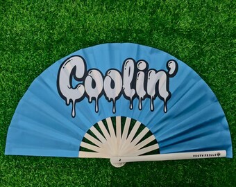 Może przedstawiać: Jasnoniebieski wachlarz z napisem "Coolin'" w białej, ociekającej czcionce. Wachlarz ma białą rączkę i biało-kremową podstawę wachlarza. Na rączce wydrukowano tekst "FESTY FRILLS".