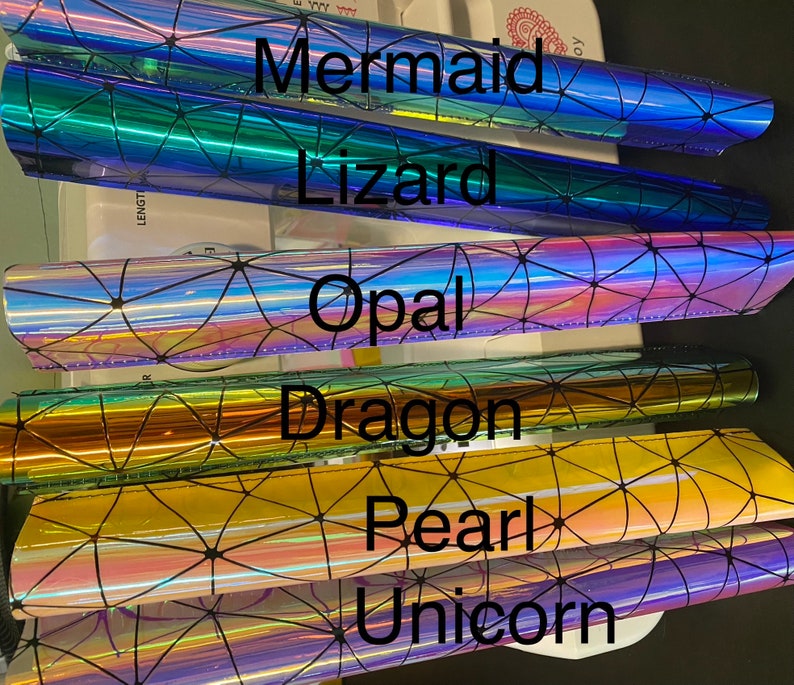 Puede incluir: Seis l&aacute;minas de vinilo iridiscente con un patr&oacute;n geom&eacute;trico y las palabras "Mermaid", "Lizard", "Opal", "Dragon", "Pearl" y "Unicorn" impresas en ellas.