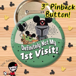 May include: A 3-inch round pinback button featuring a green background and a graphic of a character in a silver helmet and a small green creature with large ears, both wearing mouse-ear hats. The text reads, Definitely Not My 1st Visit!