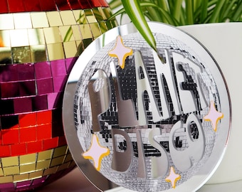 May include: A silver mirror with a disco ball design and the text "Planet Disco" in white letters with pink and orange accents.