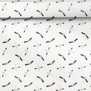 Op de afbeelding: Witte stof met een herhalend patroon van gestileerde kraanvogels in vlucht. De kraanvogels hebben beige lichamen en zwarte vleugels, wat een contrasterend ontwerp creëert. De stof is opgerold.