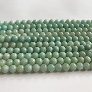 May include: A strand of smooth, round, light green beads. The beads are made of natural stone and have a subtle shimmer.