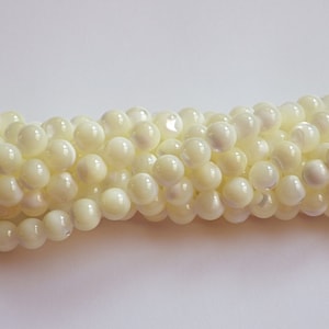 May include: A strand of white iridescent shell beads. The beads are round and have a smooth, polished finish.