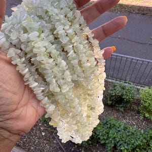 Pu&ograve; includere: Una collana a pi&ugrave; fili composta da numerose piccole pietre levigate di colore verde pallido. Le perline sono di forma irregolare e traslucide, creando un aspetto strutturato. I fili sono raggruppati insieme per formare un pezzo voluminoso.