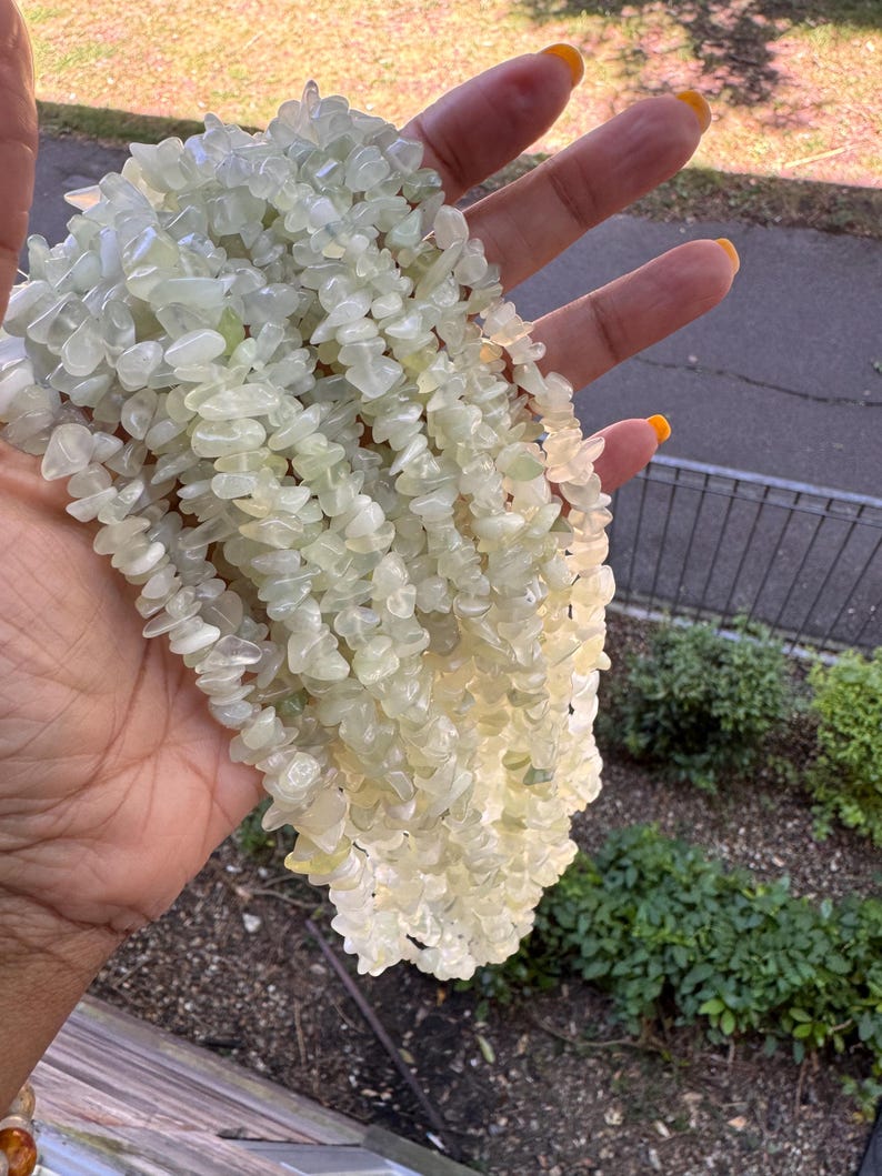 Pu&ograve; includere: Una collana a pi&ugrave; fili composta da numerose piccole pietre levigate di colore verde pallido. Le perline sono di forma irregolare e traslucide, creando un aspetto strutturato. I fili sono raggruppati insieme per formare un pezzo voluminoso.