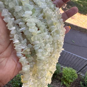 Pu&ograve; includere: Una collezione di molteplici fili di frammenti di pietra verde chiaro, pallidi e traslucidi. Le piccole pietre levigate di forma irregolare sono infilate insieme, creando un aspetto strutturato e riflettente con varie tonalit&agrave; di menta tenue e crema.
