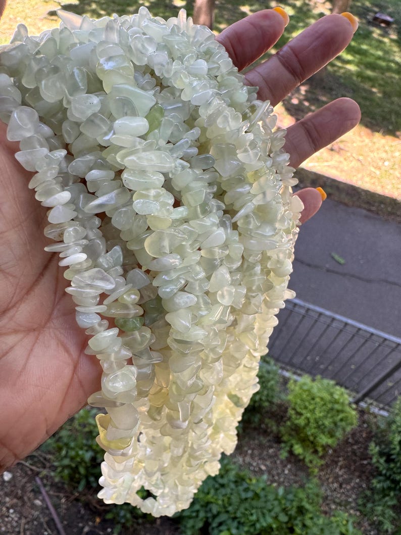 Pu&ograve; includere: Una collezione di molteplici fili di frammenti di pietra verde chiaro, pallidi e traslucidi. Le piccole pietre levigate di forma irregolare sono infilate insieme, creando un aspetto strutturato e riflettente con varie tonalit&agrave; di menta tenue e crema.
