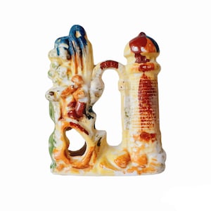 May include: A ceramic aquarium ornament featuring a lighthouse and a whimsical, colorful, multi-level structure with a hole in the center.