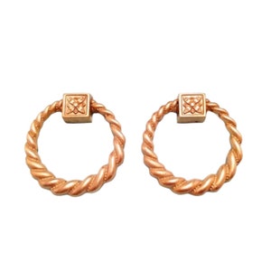 May include: Two gold-toned rope-style ring pulls with a square design in the centre.