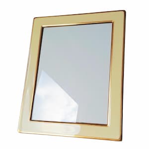 May include: A rectangular photo frame with a cream-colored border and a gold-colored inner trim. The frame has a glass insert and is angled slightly towards the viewer, showcasing its glossy finish. The frame is designed to hold a photograph.