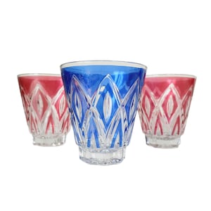 Puede incluir: Tres vasos decorativos con un diseño de cristal tallado. Un vaso es azul y dos son rosas. Los vasos tienen una base transparente y un patrón decorativo. Los vasos son adecuados para servir bebidas.