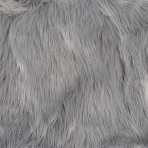 May include: Close-up of a soft, gray faux fur fabric with a subtle white sheen. The texture is fluffy and plush, resembling the look and feel of real fur.