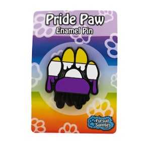 Puede incluir: Un pin de esmalte negro con forma de huella de pata con los colores de la bandera del orgullo no binario. El pin tiene rayas amarillas, blancas, moradas y negras. El texto de la tarjeta dice "Pride Paw Enamel Pin" y "Fursult Supplies.com".