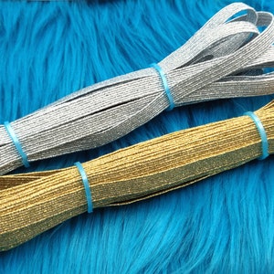 May include: Two spools of elastic trim with a sparkly finish. One spool is silver and the other is gold.