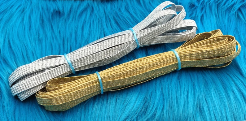 May include: Two spools of elastic trim with a sparkly finish. One spool is silver and the other is gold.