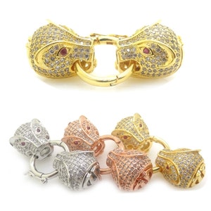 May include: A set of four gold, silver, and rose gold animal head clasps with clear and red rhinestones. The clasps are designed to look like a lion's head.