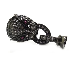 May include: Black panther head charm with clear and red rhinestones. The charm has a black metal loop for attaching to a bracelet or necklace.
