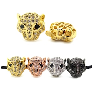 Puede incluir: Cinco abalorios de cabeza de pantera en oro, oro rosa, plata y negro con diamantes de imitación transparentes y negros. Los abalorios son para la elaboración de joyas.