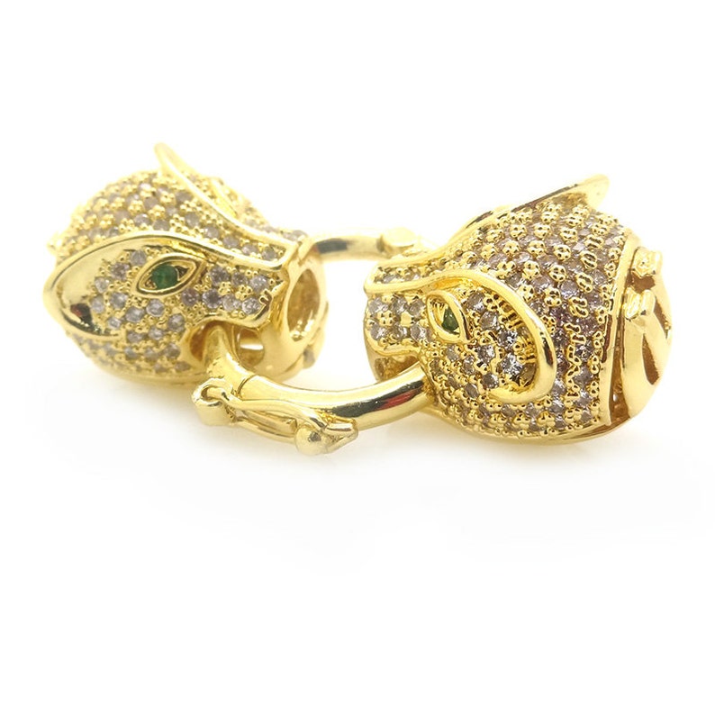May include: Gold-tone clasp with a panther head design, encrusted with clear and green cubic zirconia stones.