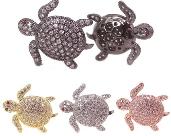 May include: Four turtle-shaped charms with a pave setting of clear rhinestones. The charms are available in black, gold, silver, and rose gold.