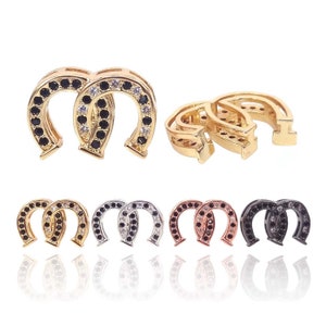 Puede incluir: Un conjunto de seis pares de pendientes en forma de herradura con piedras de circonita negra y blanca. Los pendientes están disponibles en oro, plata, oro rosa y negro.