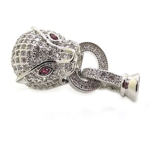 May include: Silver-toned animal head charm with clear and red rhinestones. The charm has a loop for attaching to a bracelet or necklace.