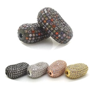 Puede incluir: Cinco cuentas ovaladas con engaste pavé de diamantes de imitación transparentes. Las cuentas son en acabados negro, plateado, oro rosa y dorado.