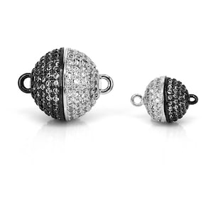 May include: Two magnetic clasps for jewelry making. One is larger and has a black and white design, the other is smaller and has a black and white design.