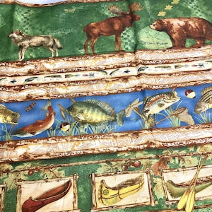 May include: A green fabric with a woodland theme. The fabric features a moose, a wolf, a bear, and a variety of fish. The fabric also includes the text "Iron Wall" and "Brown Bear".