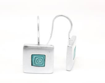 Puede incluir: Pendientes de aro de plata con un colgante cuadrado con un diseño de espiral azul turquesa.