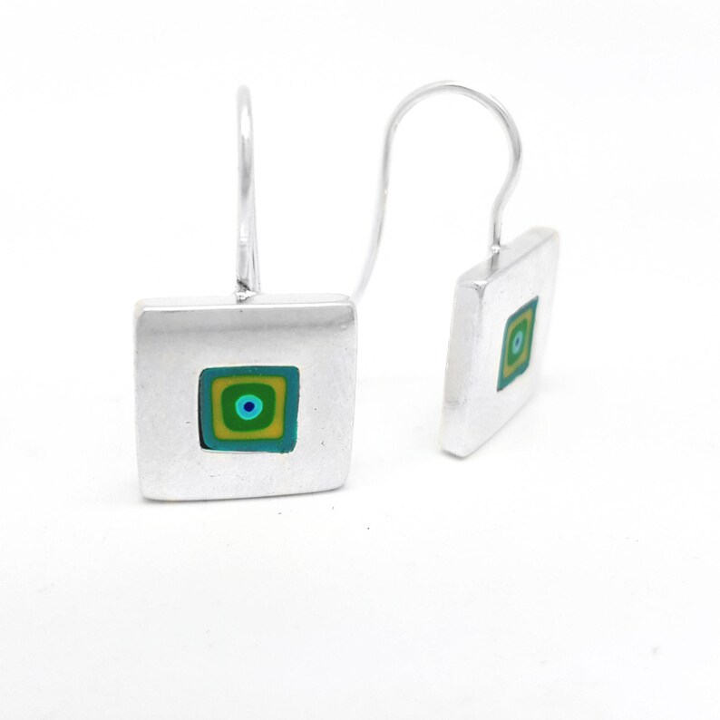 Puede incluir: Pendientes de plata con dise&ntilde;o cuadrado. El cuadrado tiene un cuadrado m&aacute;s peque&ntilde;o en el interior con un patr&oacute;n de c&iacute;rculo conc&eacute;ntrico en tonos de verde, azul y amarillo.