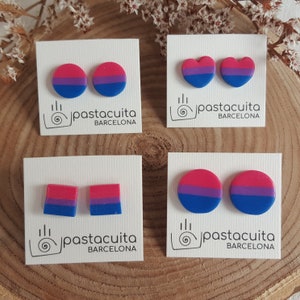 May include: Four pairs of bisexual pride earrings on white cards with the text "pastacuita BARCELONA". The earrings are in the shape of a circle, heart, and square.