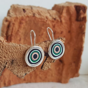 Puede incluir: Pendientes de aro de plata con un diseño de círculos concéntricos en negro, blanco, verde y naranja.