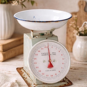 Puede incluir: Una báscula de cocina mecánica de estilo vintage con cuerpo de metal verde claro desgastado y un cuenco de esmalte blanco. El dial circular presenta números rojos, una aguja roja y el texto CAPACITY 20kg GRADUATION 100g MADE IN CHINA.