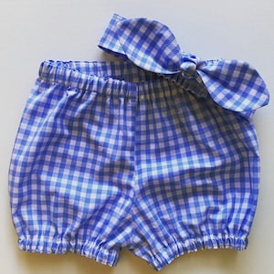 May include: Blue and white gingham baby bloomers with a matching bow tied at the waist.
