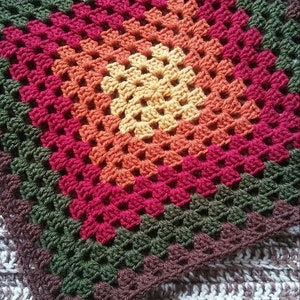 May include: A 15-inch square crochet pattern in a granny square design. The square features concentric rows of colors, including yellow, orange, red, green, and brown. The text "15" Granny Square CROCHET PATTERN Design by EyeLoveKnots" is visible.