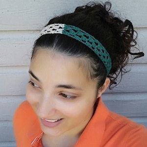 Puede incluir: Una mujer lleva una diadema de ganchillo verde y blanca. La diadema está hecha de dos colores diferentes de hilo, con una sección blanca en la parte delantera y una sección verde en la parte trasera. La mujer lleva una camiseta polo de color naranja brillante.