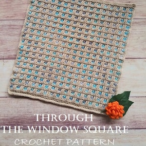 May include: A crocheted square with a beige, blue, and gray color pattern. The square is on a wooden surface and the text "THROUGH THE WINDOW SQUARE CROCHET PATTERN" is below the square.