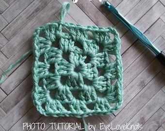 May include: A photo tutorial on how to crochet a granny square. The image shows a teal granny square with a crochet hook lying next to it.