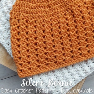 Op de afbeelding: Een close-up van een gehaakte beanie in een verbrand oranje kleur. De beanie is gemaakt met een eenvoudig steekpatroon en heeft een textuur. De tekst "Selene Beanie Easy Crochet Pattern - EyeLoveKnots" is zichtbaar onderaan de afbeelding.