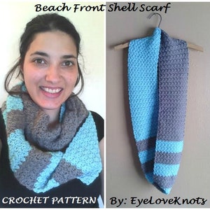 May include: A crochet scarf pattern called "Beach Front Shell Scarf" by EyeLoveKnots. The scarf is made with two colors of yarn, a light blue and a gray. The scarf is shown being worn by a person and hanging on a hanger.