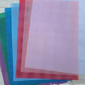 May include: A selection of coloured plastic canvas sheets, including purple, green, blue, and red. The sheets have a grid pattern and are ideal for needlecraft projects. The text "YARN CRAFTS & COFFEE" is visible in the bottom right corner.